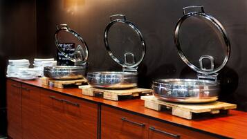 A buffet setup with multiple serving stations, each with a glass lid and a metal bowl.