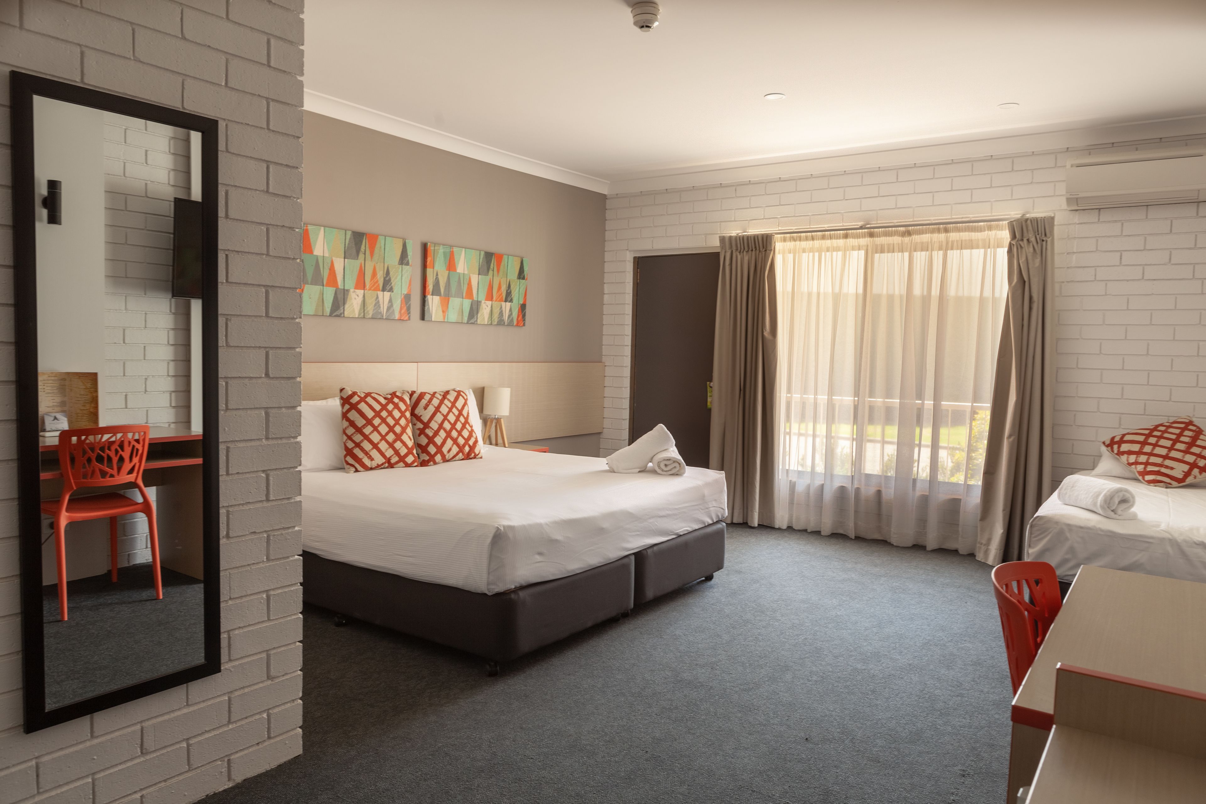 Una habitación de hotel con cama, escritorio, silla y una obra de arte en la pared.