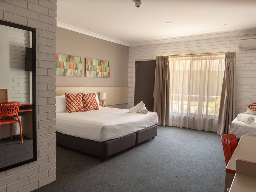 Una habitación de hotel con cama, escritorio, silla y una obra de arte en la pared.