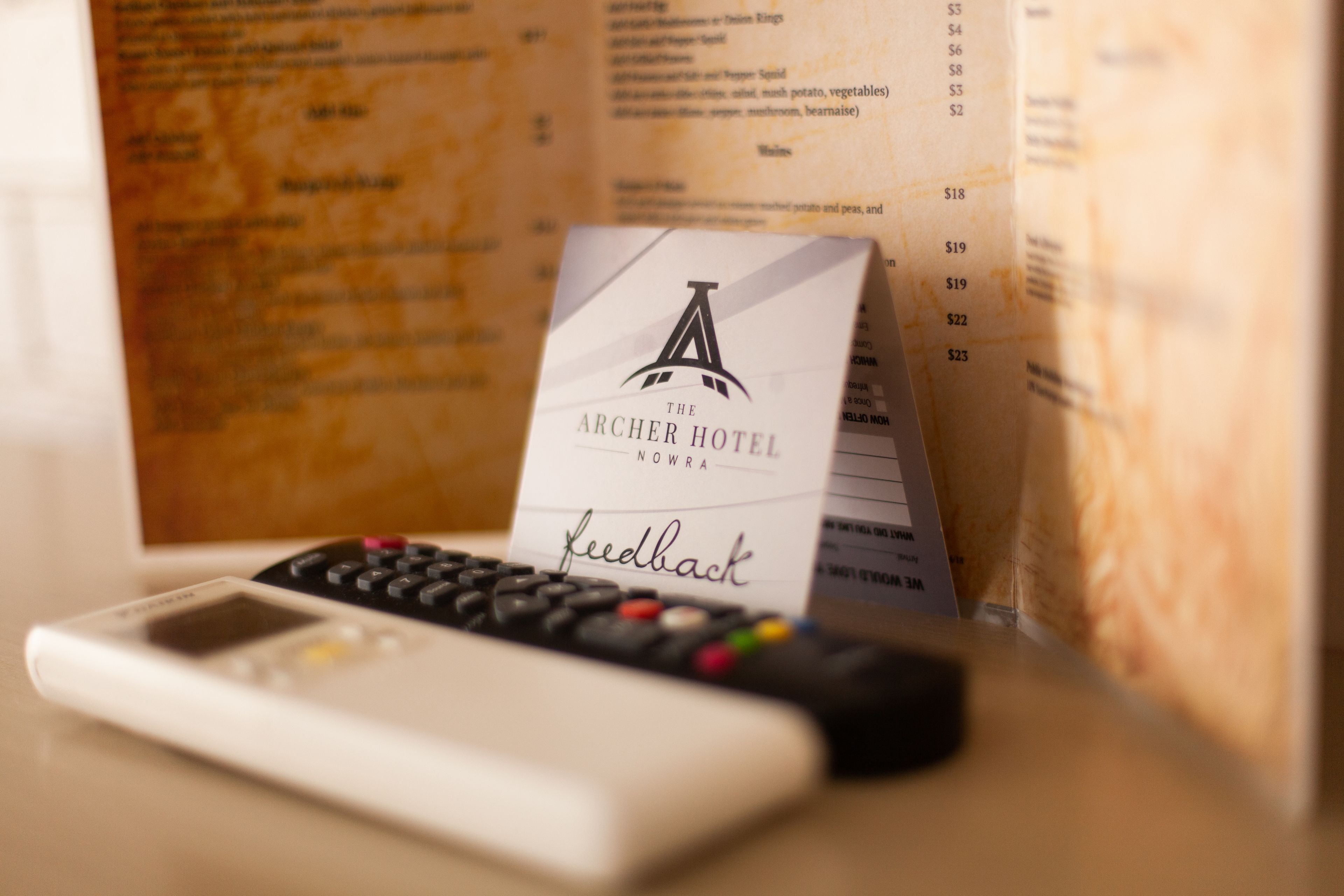 Een afstandsbediening en een feedbackkaart van The Archer Hotel.