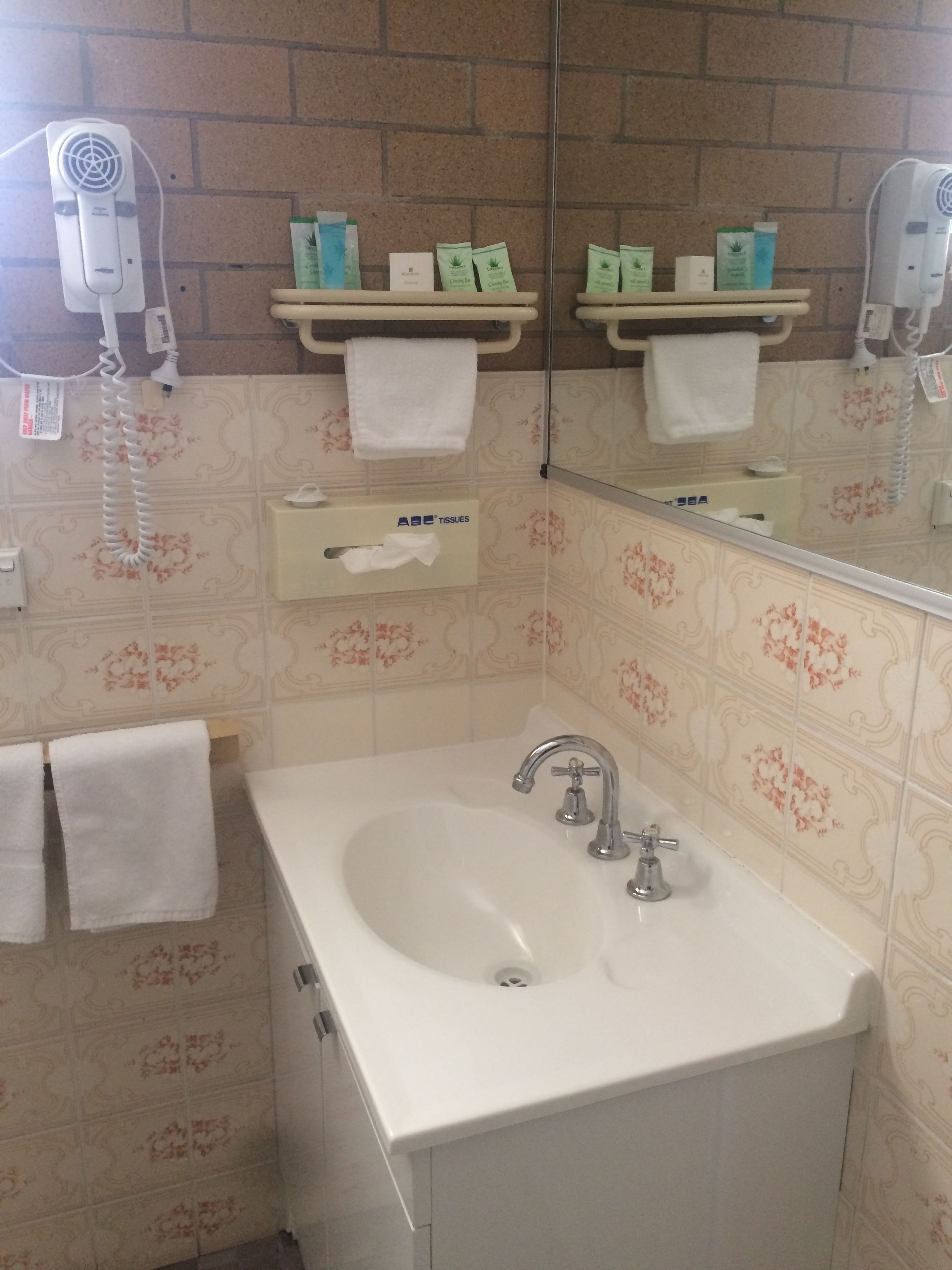 Ein Badezimmer mit Waschbecken, Spiegel und Pflegeprodukten.