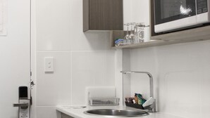 A modern kitchen with white cabinetry, a stainless steel sink, a microwave, and a built-in oven. - Aston Motel Yamba (Yamba)
