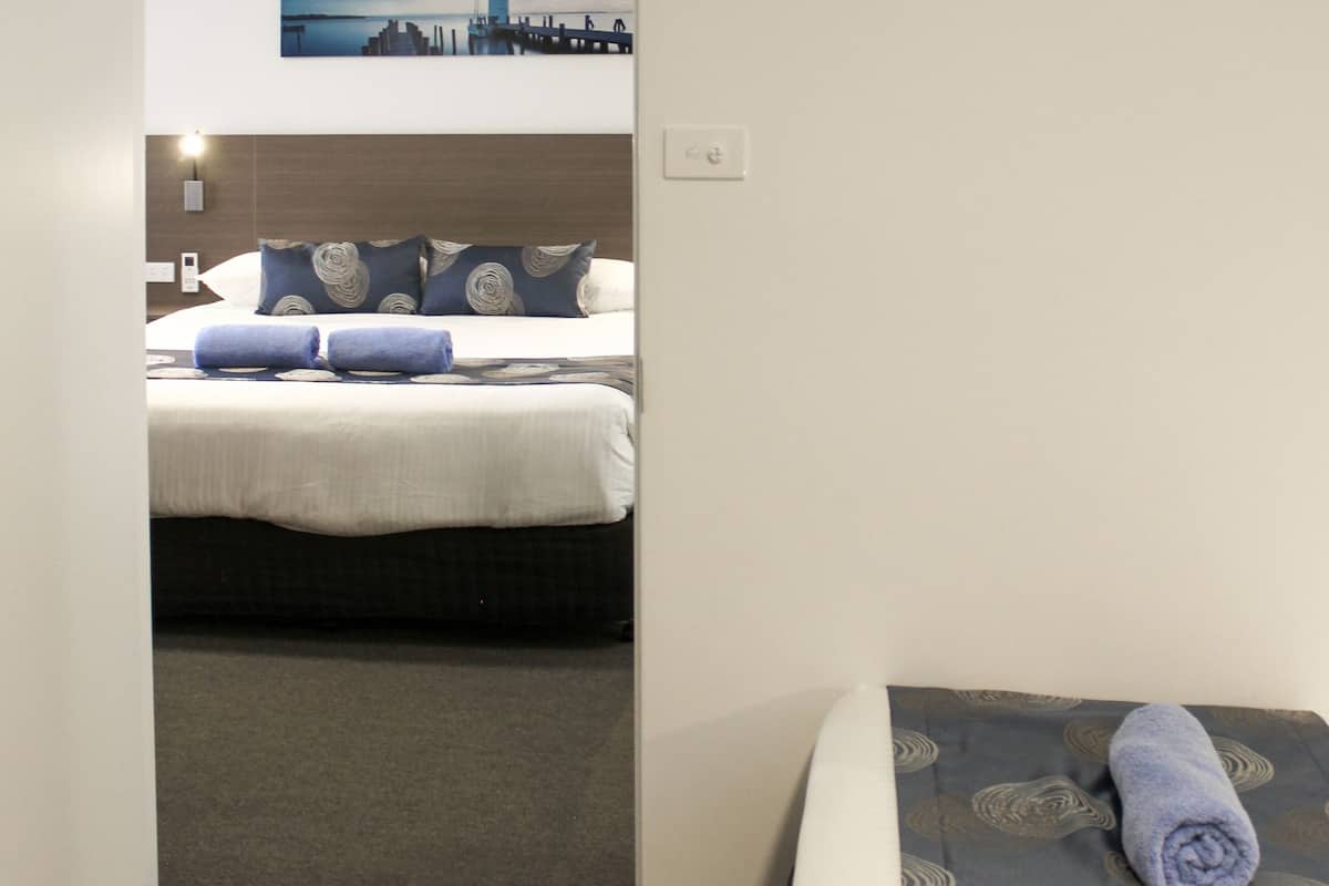 Habitación de hotel con una cama, vistas a un paisaje urbano y una puerta que da a otra habitación.