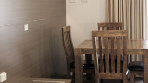 A dining area with a wooden table and chairs, a flat-screen TV mounted on the wall, and a light fixture above the table. - Aston Motel Yamba (Yamba)