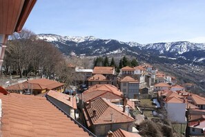 A mountainous village with traditional red-tiled roofs and buildings clustered together. - Kassaros (Metsovo)