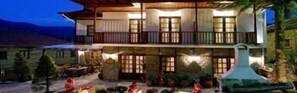 A two-story building with a balcony, a stone facade, and a well-lit entrance. - Kassaros (Metsovo)