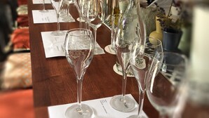 A long table with multiple wine glasses and bottles, likely in a bar or restaurant setting.