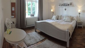 A bedroom with a bed, bedside tables, a chair, a window, and a radiator.