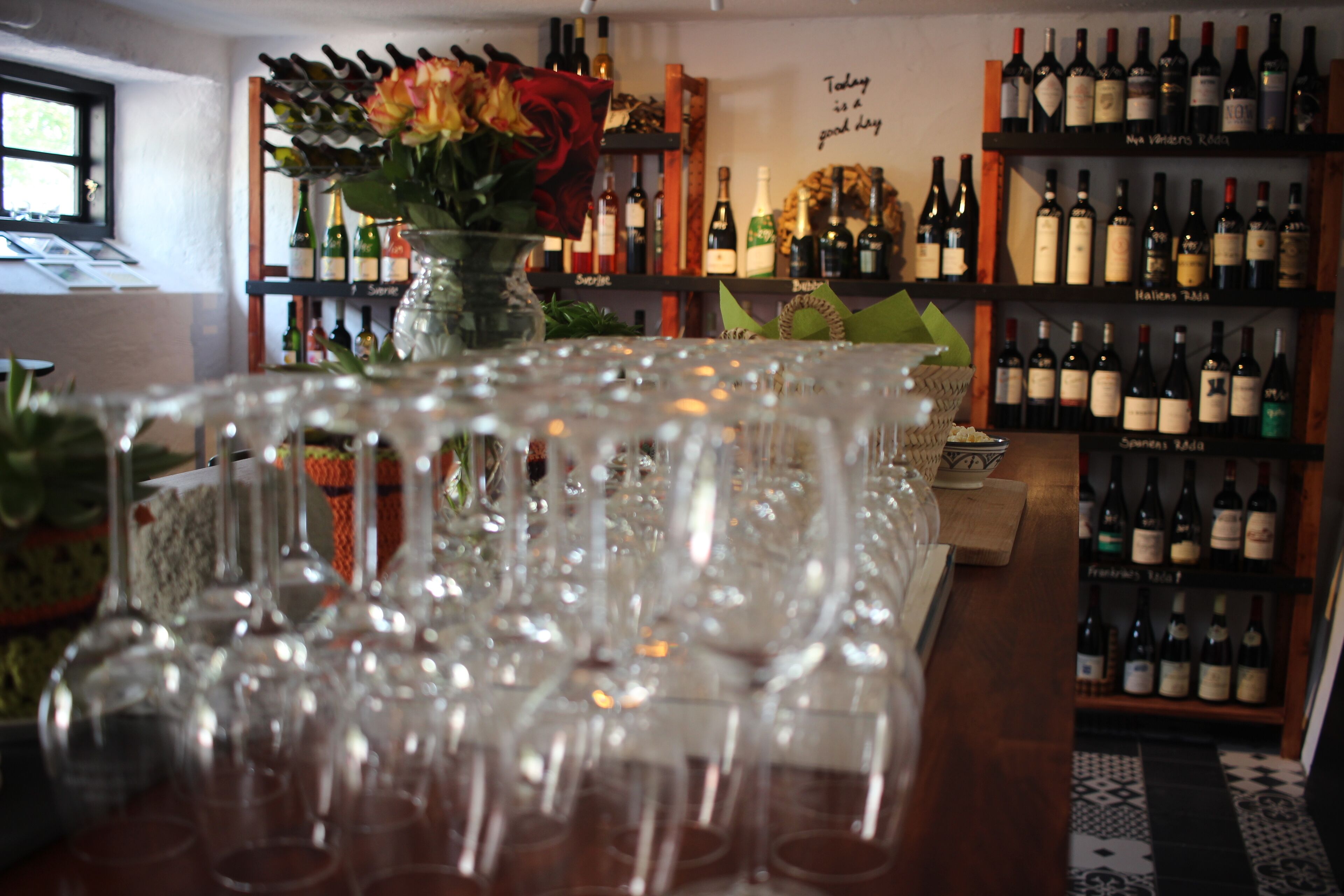 Una zona de bar con numerosas botellas de vino en estantes y una variedad de copas de vino sobre la barra.