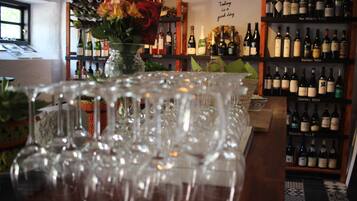 Una zona de bar con numerosas botellas de vino en estantes y una variedad de copas de vino sobre la barra.
