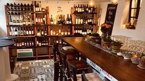 A bar area with a variety of wine bottles on shelves, a patterned floor, and several bar stools.