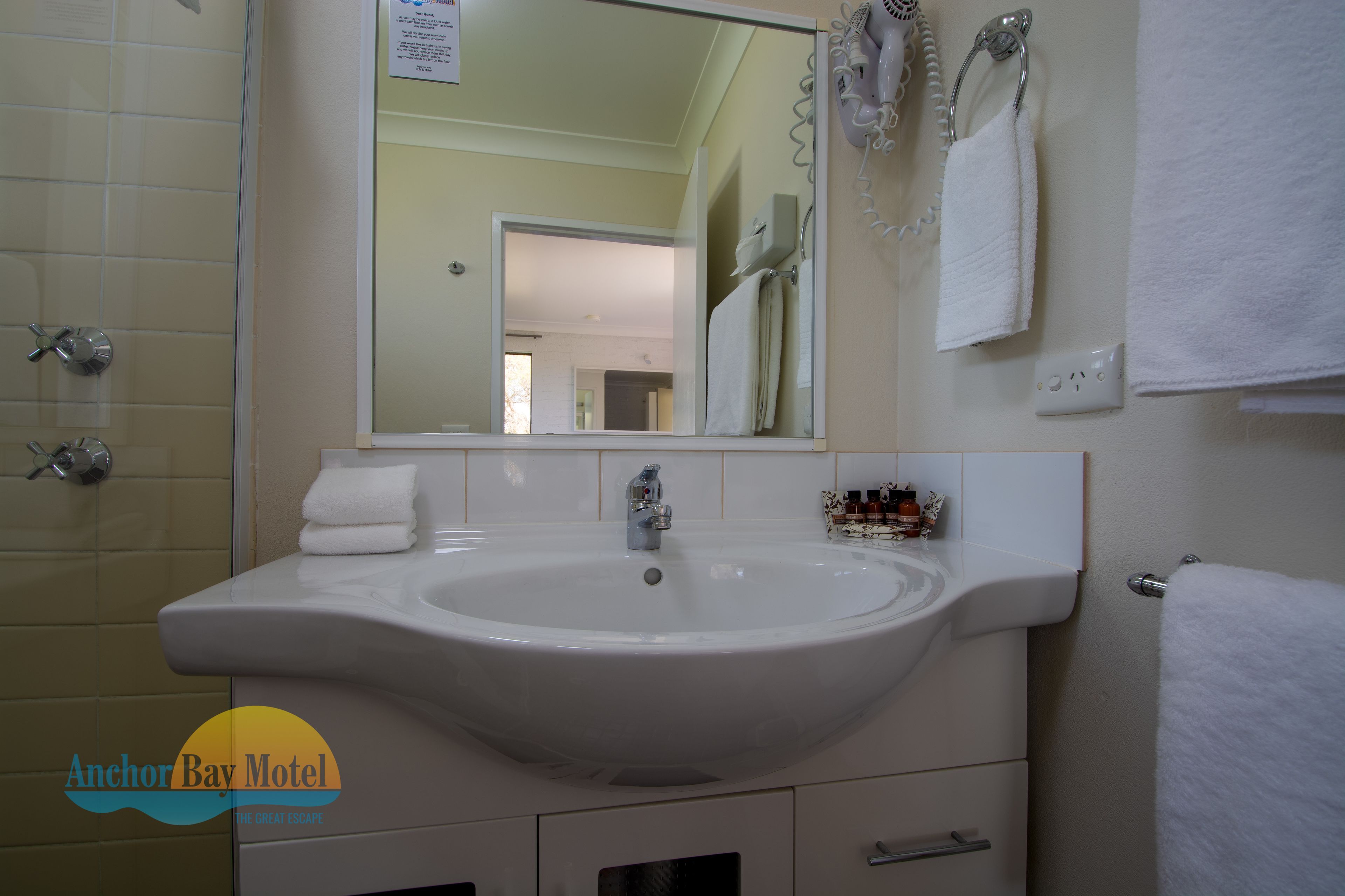 A bathroom with a large sink, a mirror, and a towel rack.