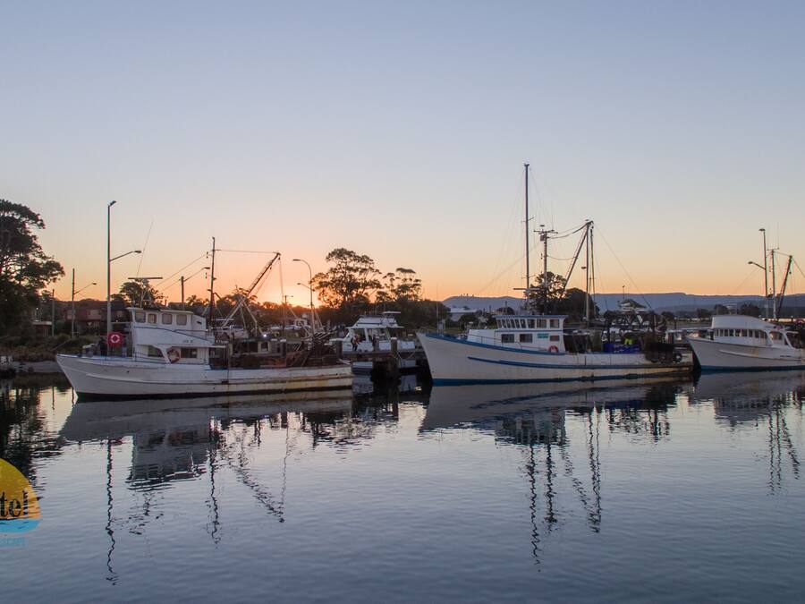 Un puerto deportivo con varios barcos amarrados al atardecer.