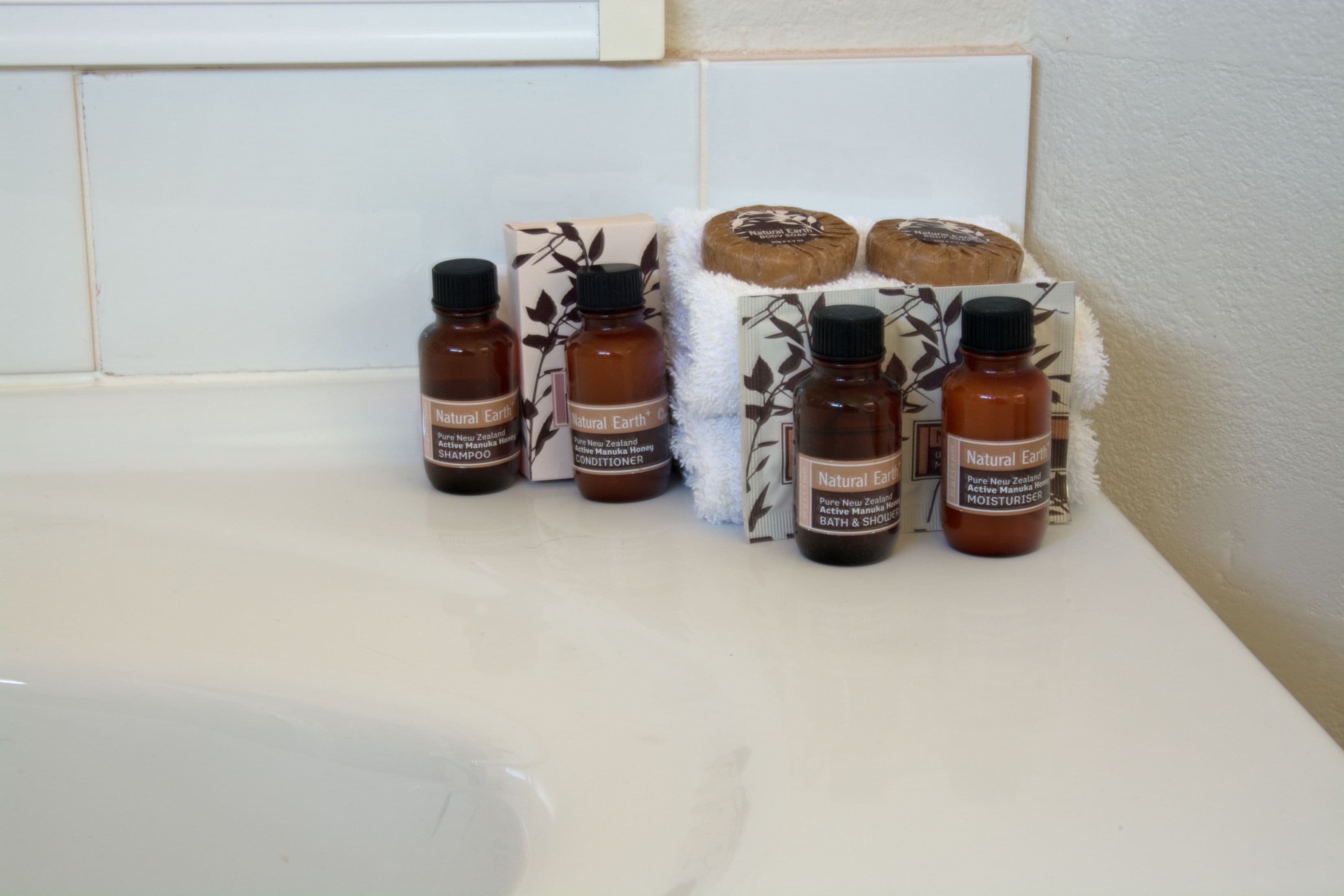 A bathroom shelf with various toiletries including bottles of shampoo, conditioner, and a bar of soap.