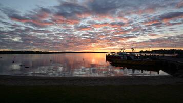 A sunset over a calm lake with a dock and boats.