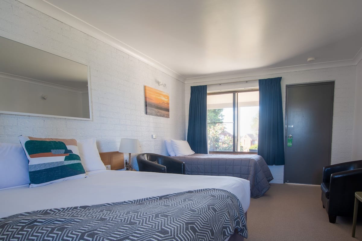 Quarto de hotel com duas camas, uma escrivaninha e uma cadeira.