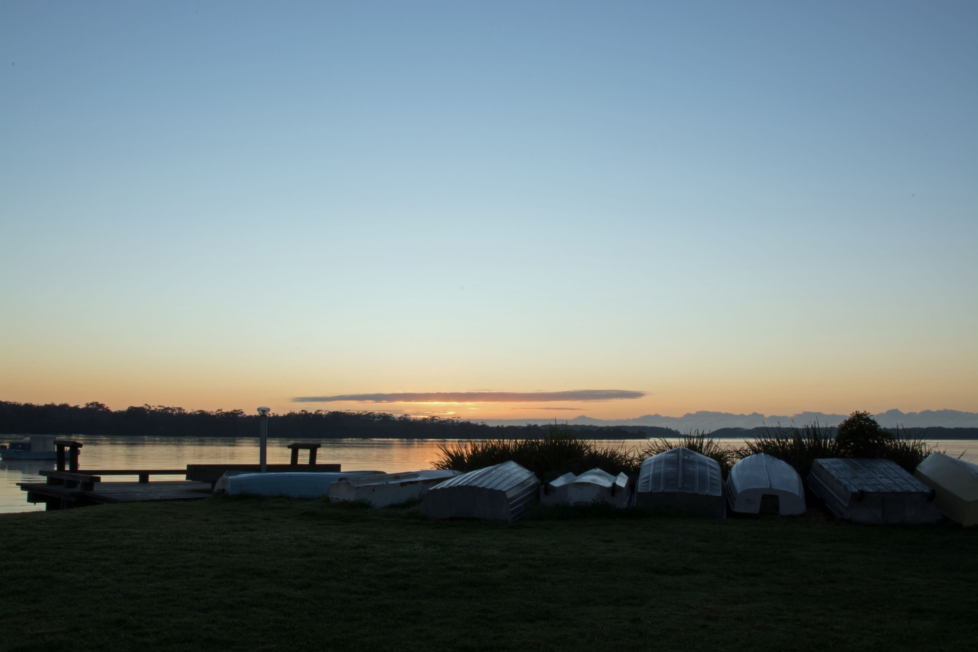 A lakeside view with several tents and a dock.