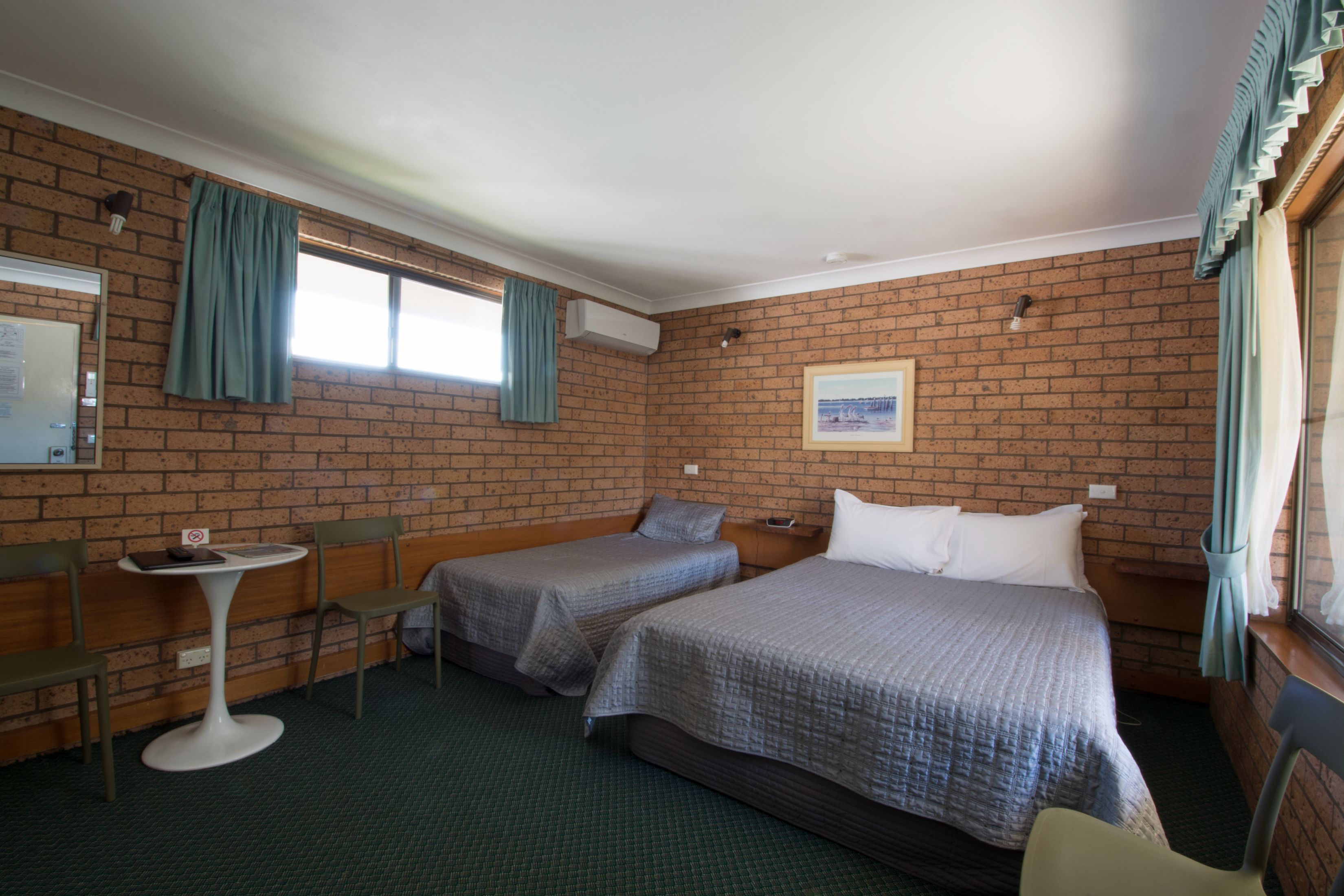 A room with two beds, a small table, and a chair.