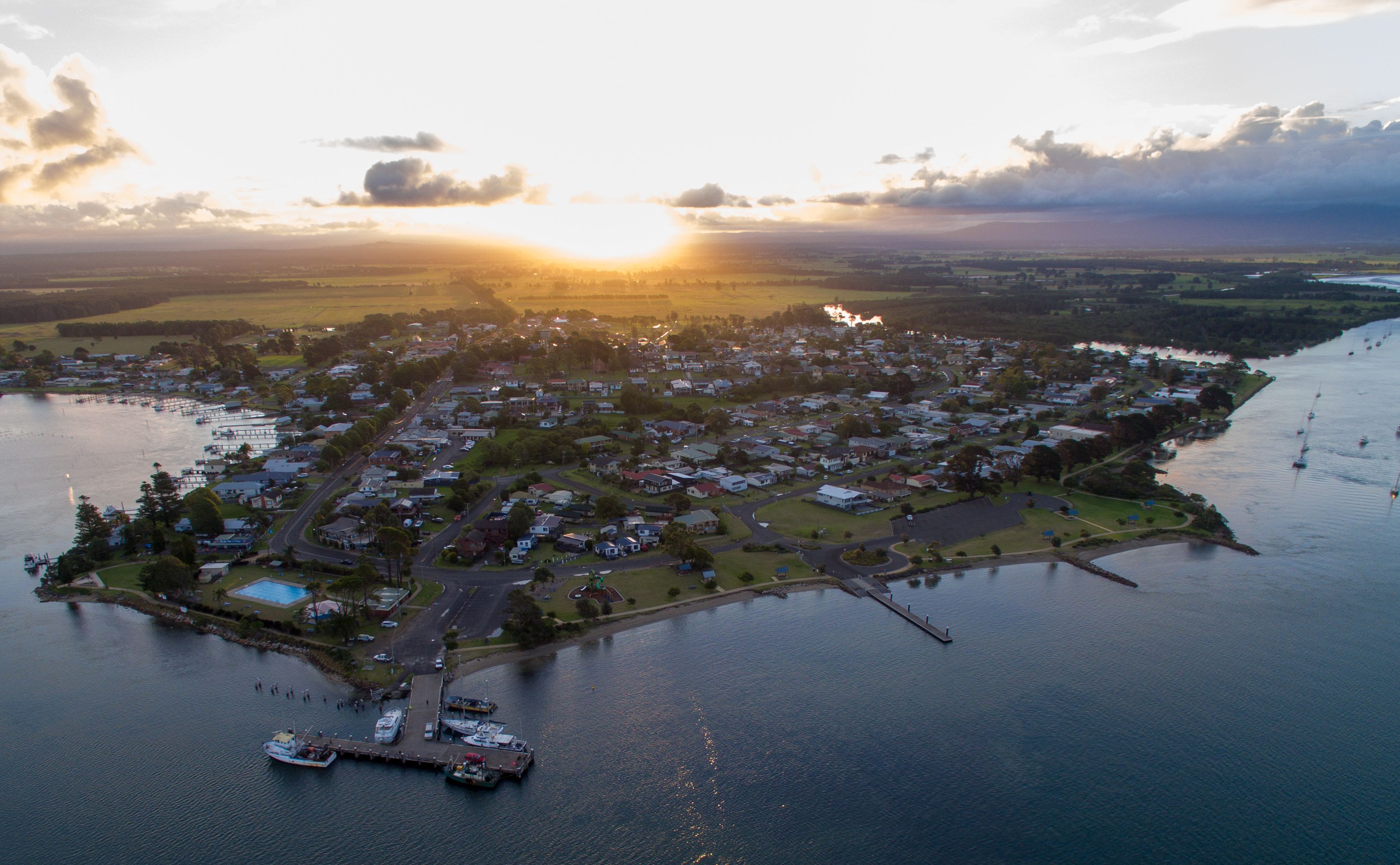An aerial view of a coastal town with a marina, residential areas, and a large body of water.