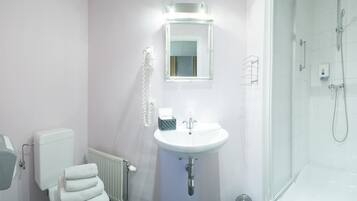 Un baño con lavamanos, espejo y ducha blancos.