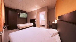 A hotel room with a large bed, a smaller bed, a TV, a desk with a chair, and a wardrobe. - Alpha Hotel (Ostend)