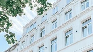 A white building with the sign "ALPHA HOTEL" above the entrance. - Alpha Hotel (Ostend)