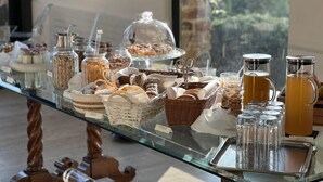 Un bufé de desayuno con diversas opciones de comida y bebidas sobre una mesa de vidrio.