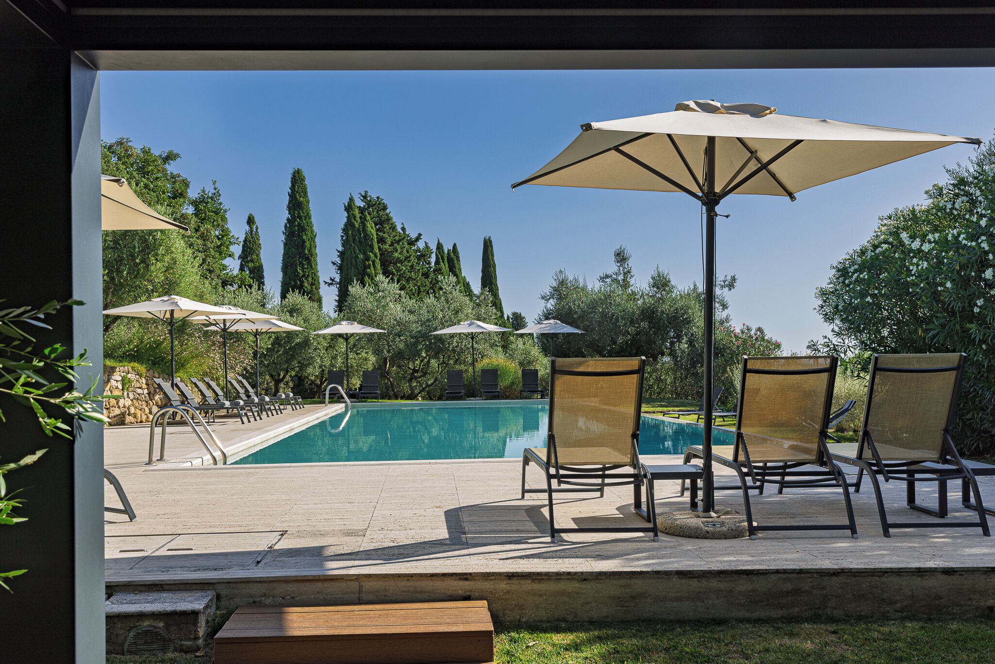 Area piscina con lettini e ombrelloni, cielo sereno e piscina.