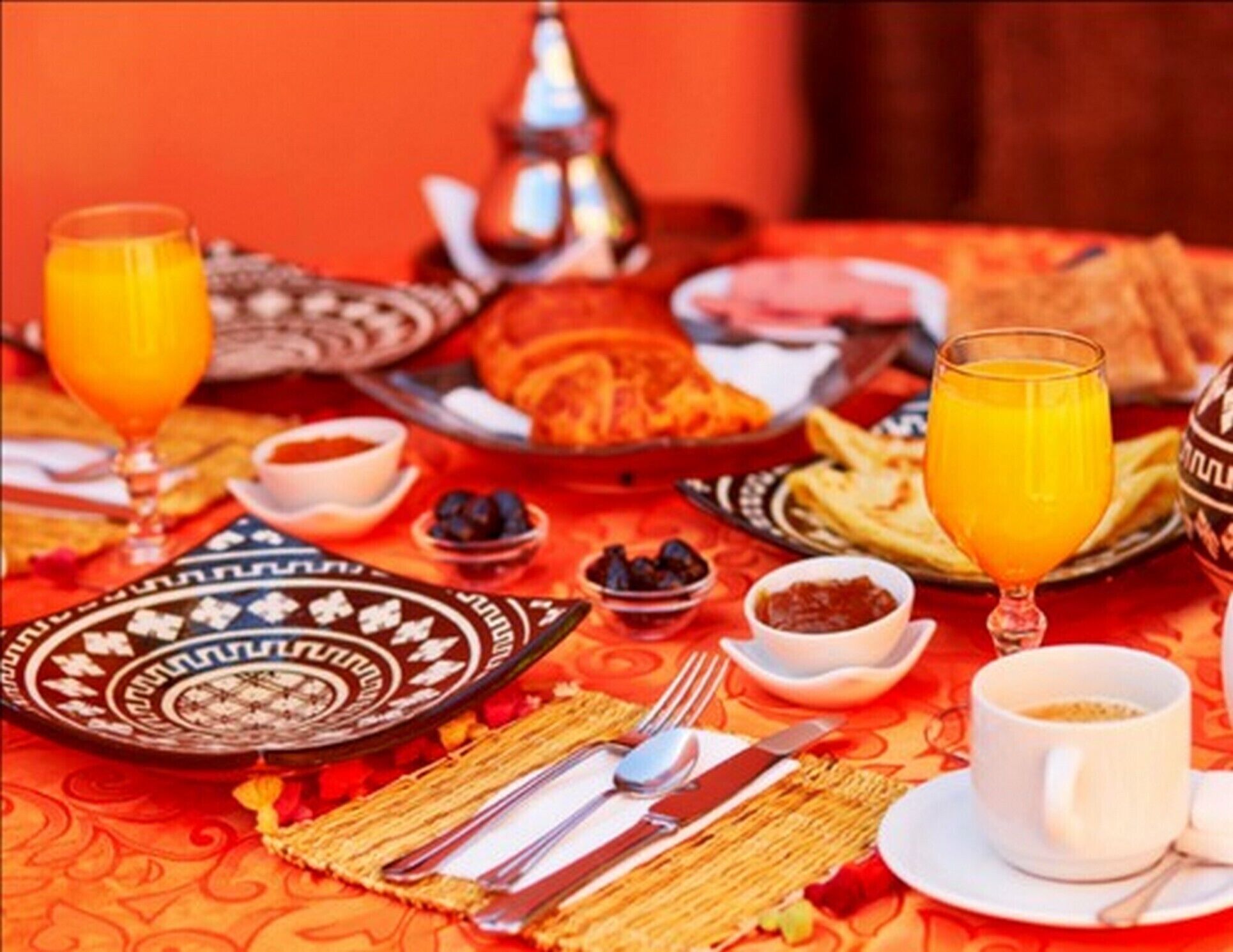 Een ontbijttafel met borden eten, glazen sinaasappelsap en een kop koffie.