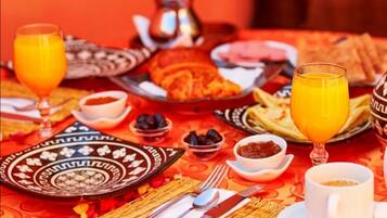 Een ontbijttafel met borden eten, glazen sinaasappelsap en een kop koffie.
