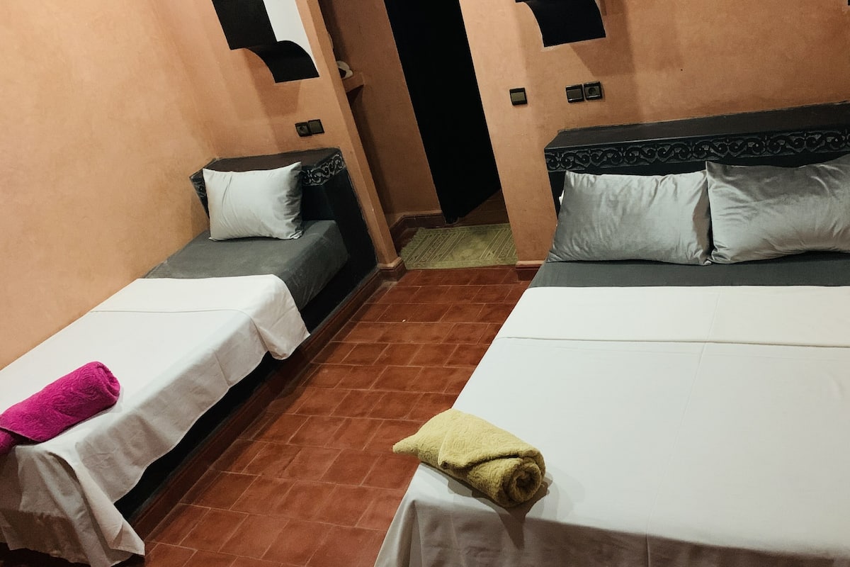 Une chambre d’hôtel avec deux lits simples, un grand lit et un petit canapé.