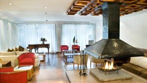 A modern living room with a stone fireplace, wooden flooring, and red and white furniture.