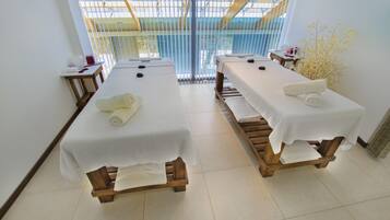 Relax in a serene spa room with two massage tables, a large window offering a peaceful view, and a tranquil atmosphere.