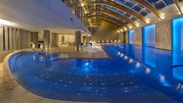 Una piscina cubierta, una piscina al aire libre, tumbonas