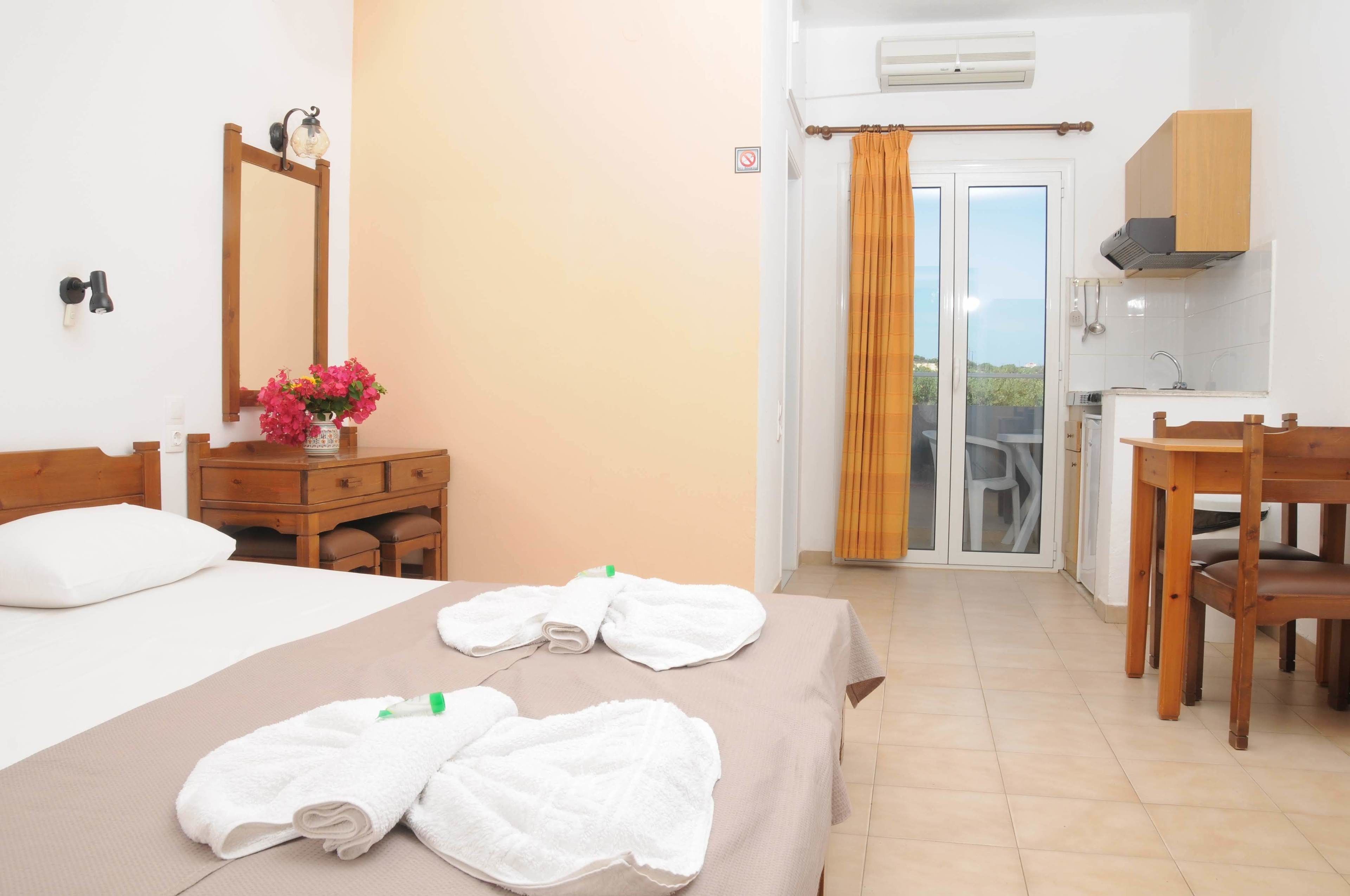 A hotel room with a bed, a desk, a chair, a bathroom with a shower, and a balcony with a view.