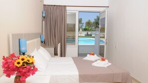 Habitación de hotel con cama, un jarrón de flores y vistas a una piscina, además de una puerta corredera al exterior.