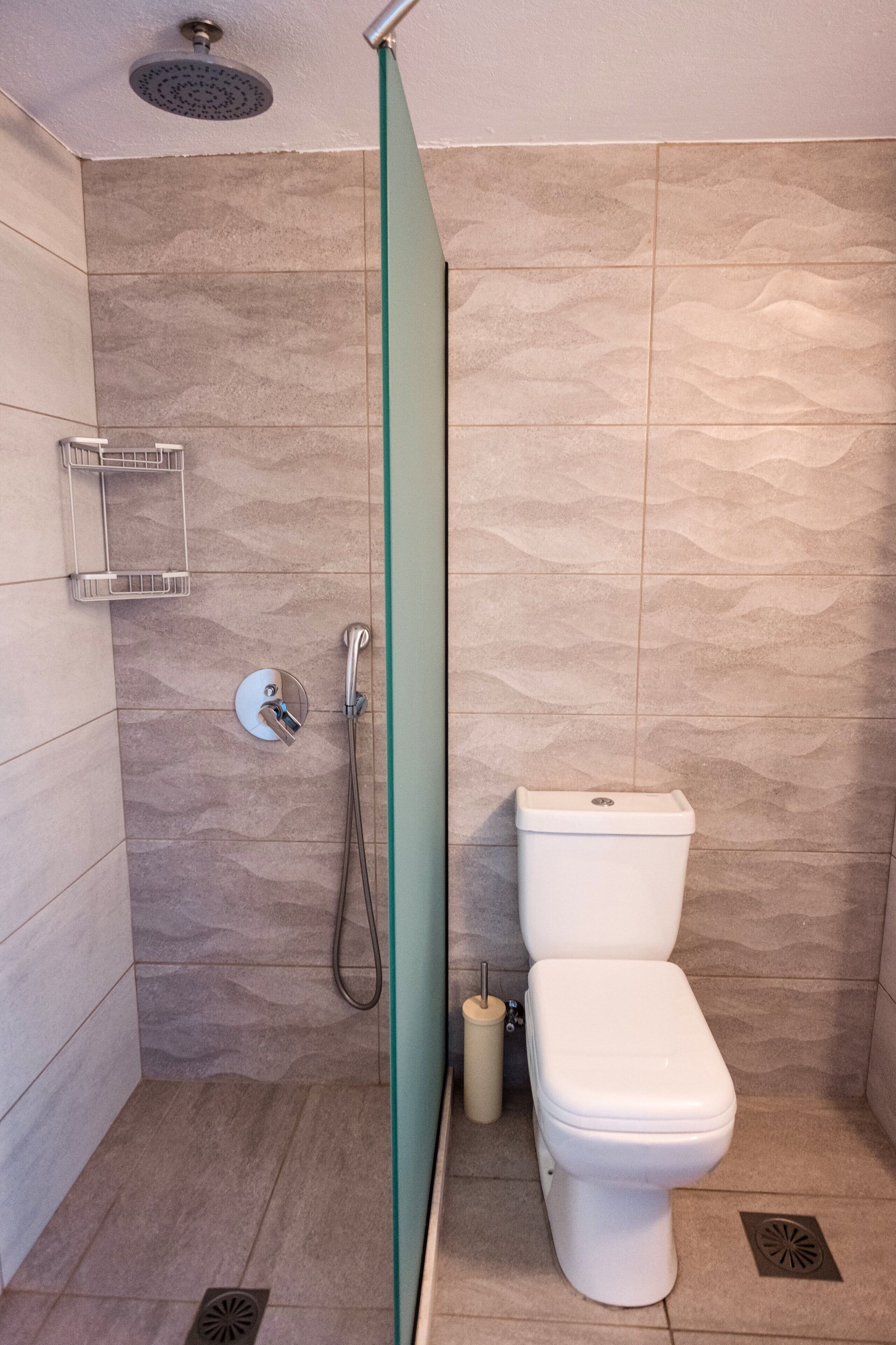 A modern bathroom with a shower, toilet, and a towel rack.