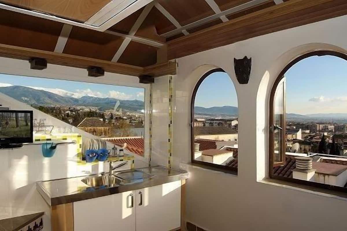 A kitchen with a large window and a view of a cityscape.