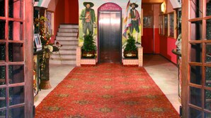 Une entrée somptueuse, ornée d’un lustre, d’une statue et d’un tapis rouge menant à une porte.