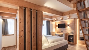 Un intérieur en bois comprenant un lit, un bureau et un téléviseur fixé au mur.