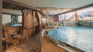 Un espace spa doté d’un sol en pierre, de sièges en bois et d’une piscine offrant une vue sur les montagnes.