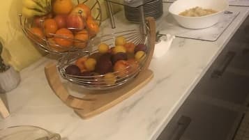 Una barra de desayuno con fruteros, una estación de café y un tazón de cereales.
