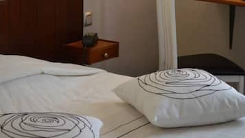 Un lit bien fait, avec une literie blanche et deux coussins décoratifs à motifs en spirale.