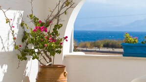 Una estructura arqueada blanca con una planta en maceta y vista al mar.