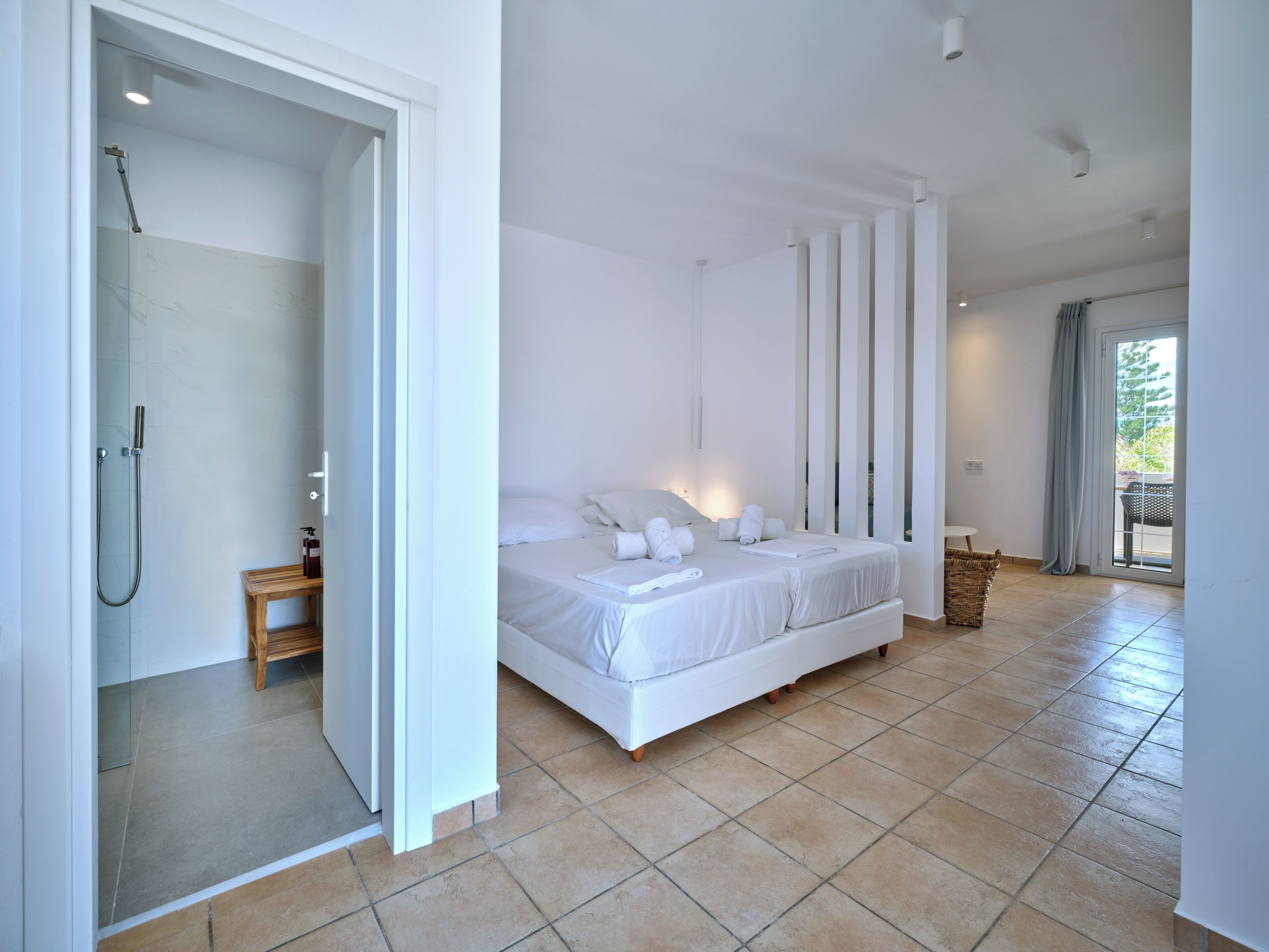 Ein modernes Schlafzimmer mit einem großen Bett, einem Nachttisch aus Holz und einer Dusche.