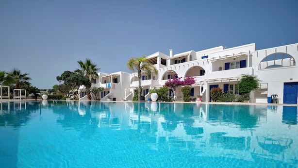 Una gran piscina cristalina con un edificio blanco al fondo.