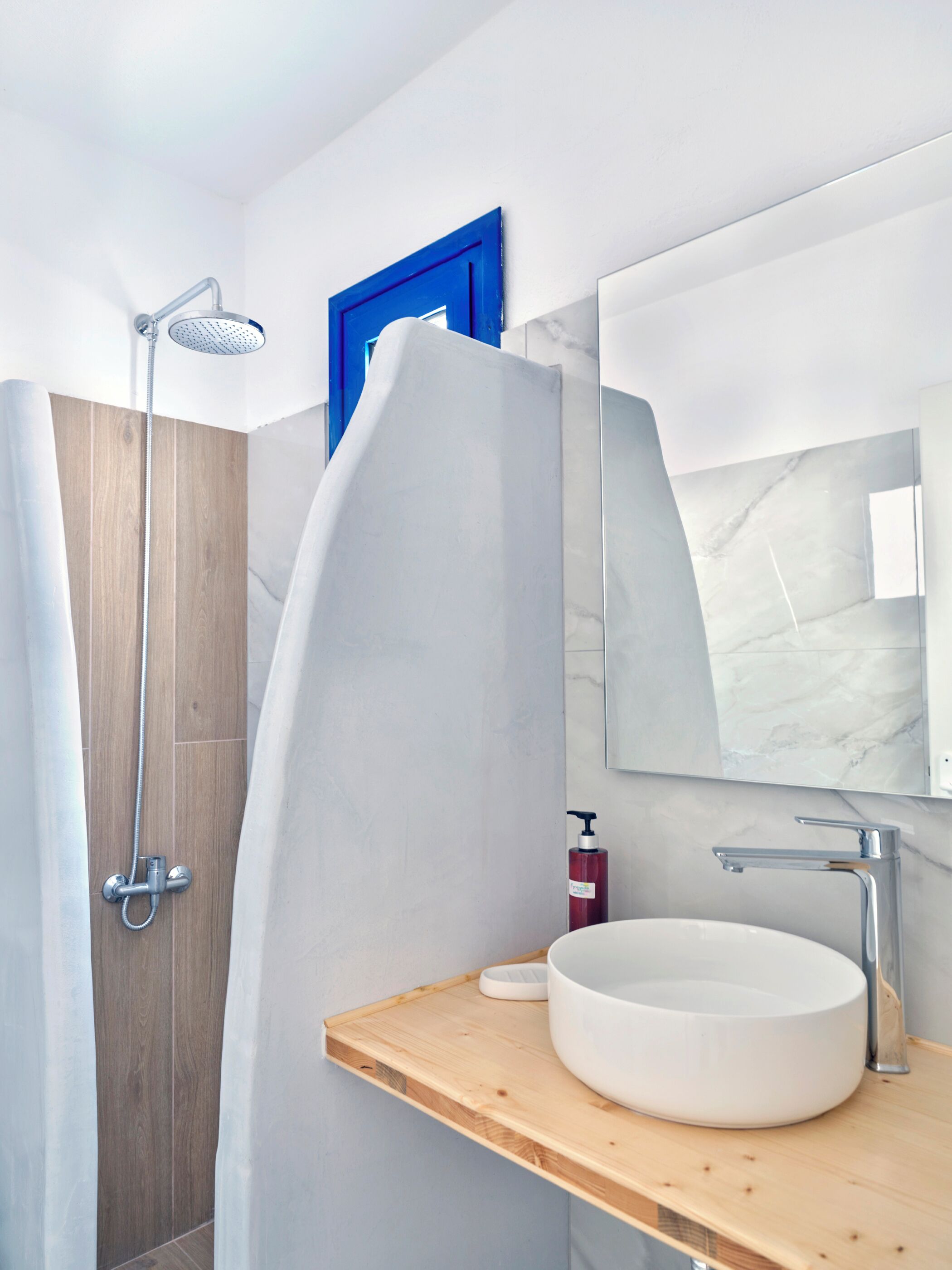 Un baño moderno con tocador de madera, un espejo grande y cabina de ducha.
