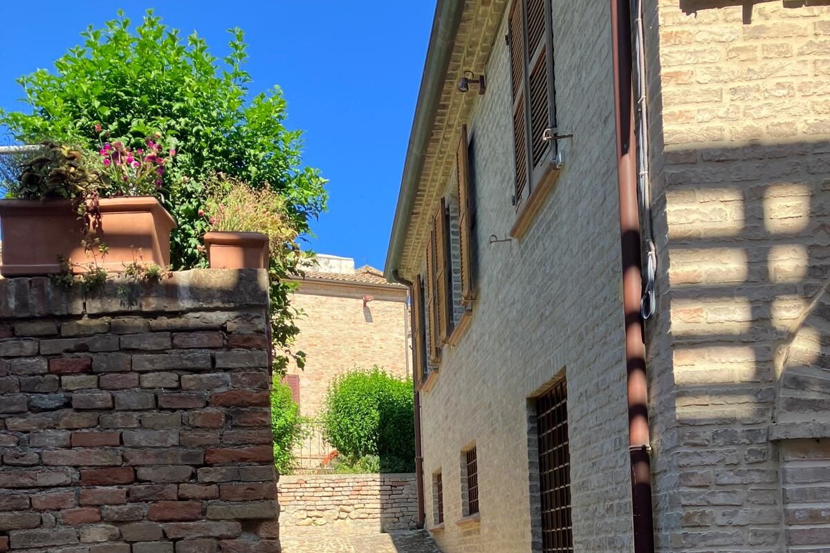 A narrow cobblestone alleyway flanked by historic buildings with brick walls and wooden shutters.