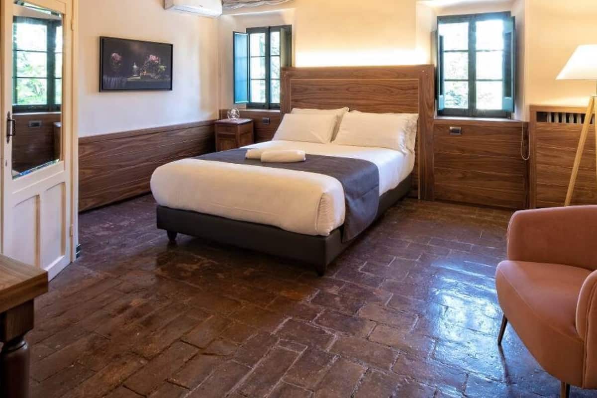 Ein Schlafzimmer mit einem Bett, einem Nachttisch aus Holz, einer Lampe und einem Sessel.