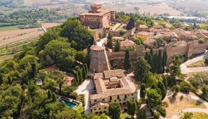 Vue aérienne d’un château historique, entouré d’une végétation luxuriante et de champs.